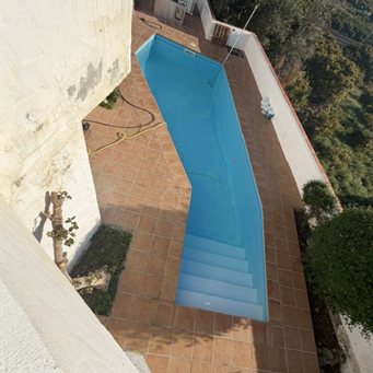 Sanierter Pool mit Einstiegstreppe auf einer Hangterrasse, von oben fotografiert