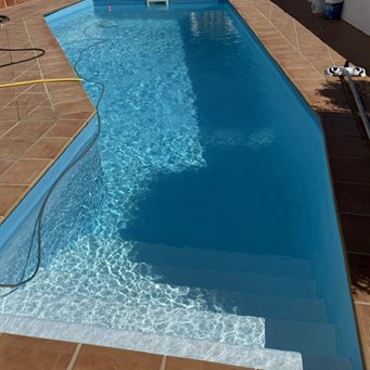 Hellblauer Pool mit breiter Einstiegstreppe und Terrakotta-Beckenrand