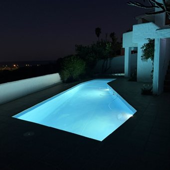Beleuchteter Pool bei Nacht auf einer Terrasse